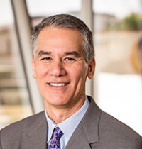 img Head-and-shoulders portrait of a smiling business professional in a gray suit and purple tie.